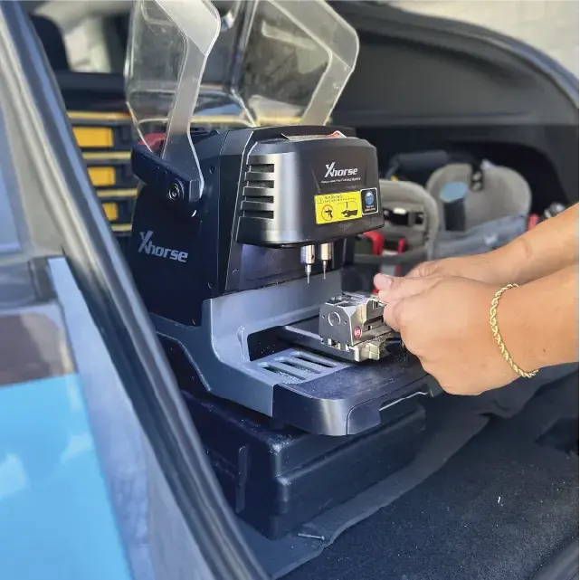Automotive locksmith performing car key replacement on-site with mobile van