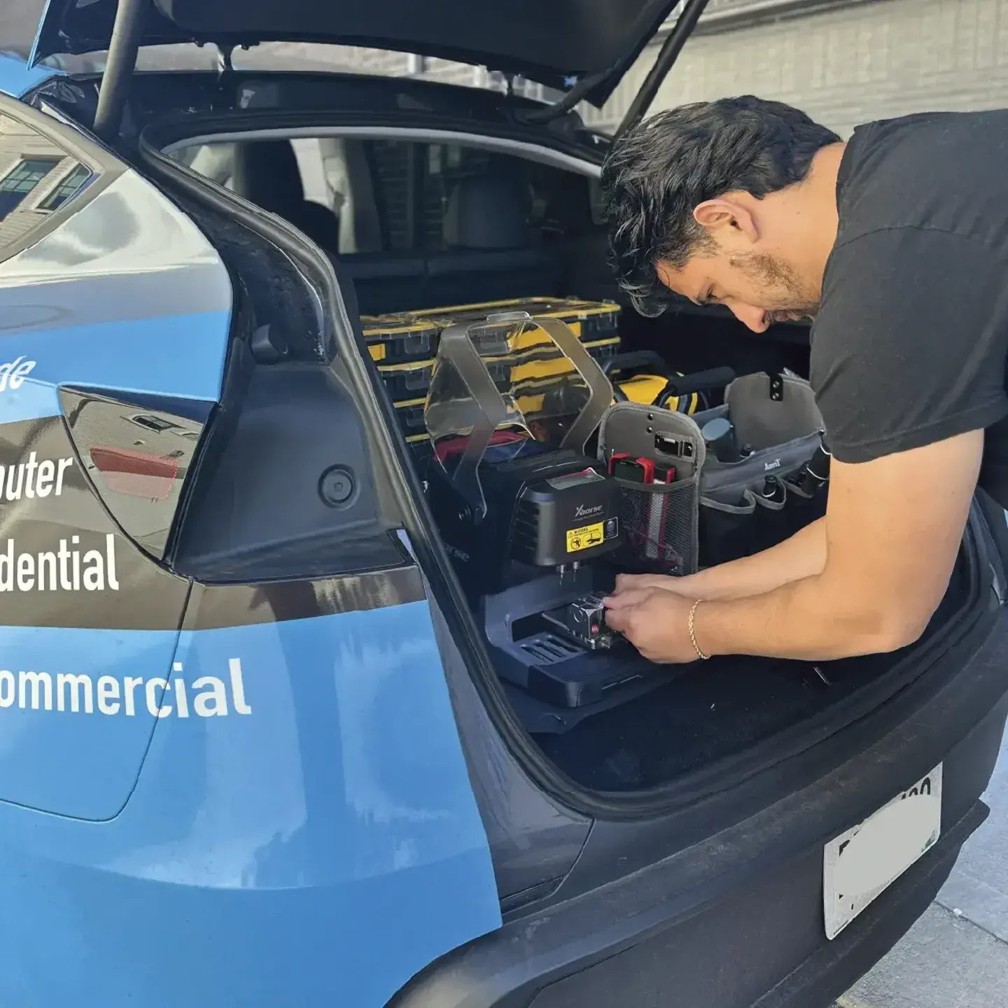 Automotive locksmith performing car key replacement on-site with mobile van